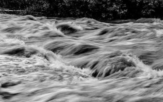 a black and white image of a rushing river